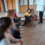 Kinder sitzen auf einer Bank und streicheln einen Hund